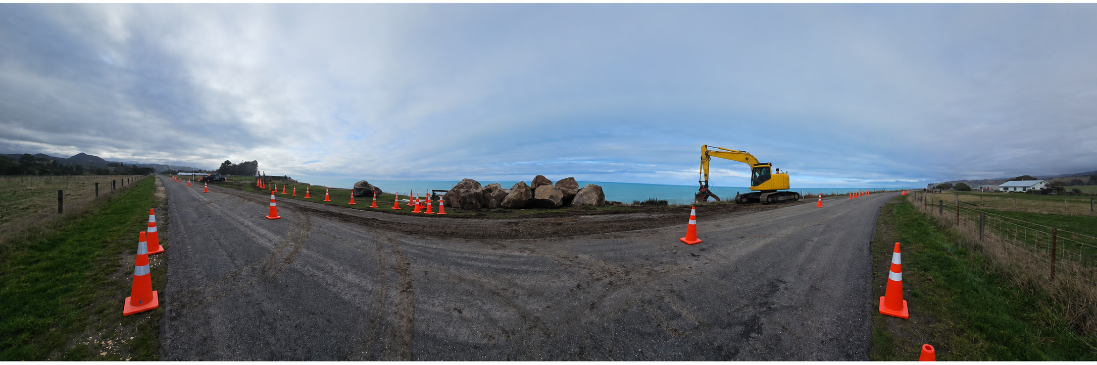 Traffic management cones protecting road works beside a New Zealand coastal corridor